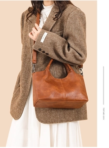 Detailed shot of caramel textured leather handbag with dual handles and shoulder strap