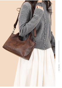 Brown vintage textured leather tote bag styled with a grey sweater and white skirt