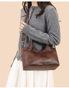 Detailed view of dark brown pebbled leather handbag with adjustable shoulder strap and handle