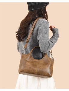 Brown leather tote bag with pebble texture and adjustable shoulder strap worn by model