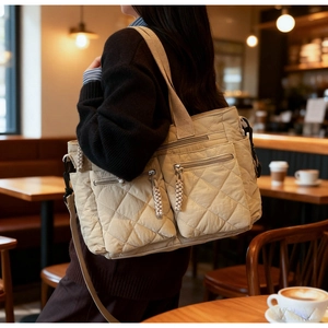 Quilted beige tote bag detail showing large diamond stitching and functional zipper pockets