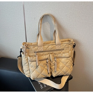 Detail of light khaki quilted tote bag with double front zippers and woven pullers