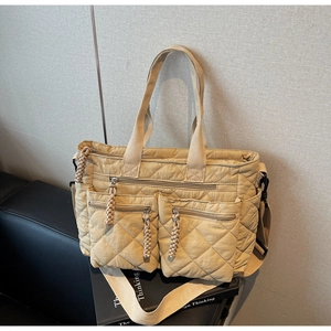 Detail of beige quilted nylon tote bag with dual front zipper pockets and top handles