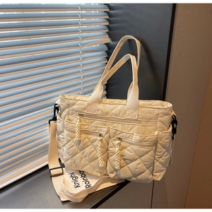 Detail of cream quilted tote bag with multi-pocket design and adjustable shoulder strap