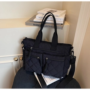 Close-up of black quilted tote bag with multi-pocket design on corduroy cushion