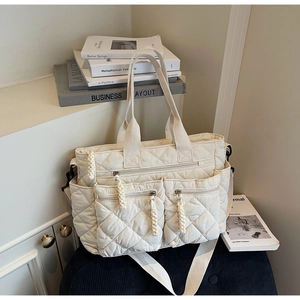 Detail view of large quilted tote bag with multiple pockets and adjustable beige strap