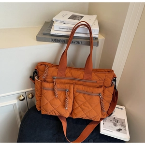 Detailed close-up of dark orange quilted tote bag with multi-pocket and waterproof texture