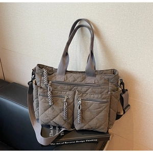 Detail of grey quilted tote bag with multi-pocket design and adjustable shoulder strap