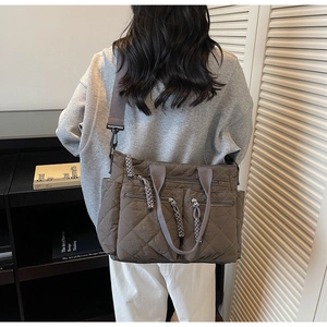 Detail of grey quilted tote bag featuring dual front zip pockets and woven knot pullers