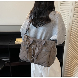 Detailed view of dark grey quilted tote bag with dual front zipper pockets and shoulder strap