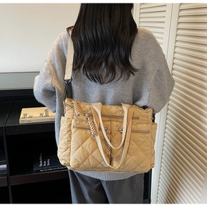 Detail of light khaki quilted nylon tote bag with multiple pockets and shoulder strap