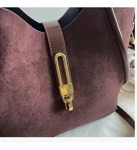 Close-up of vintage burgundy suede bucket bag with shiny gold U-shaped hardware detail