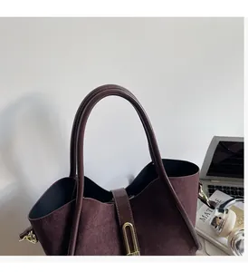Detail of suede tote bag texture with smooth leather straps and gold U-shaped buckle