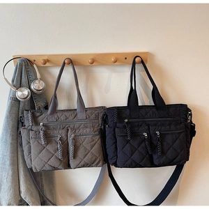 Close-up of quilted tote bag with three front zippers and woven pullers on a wall hook