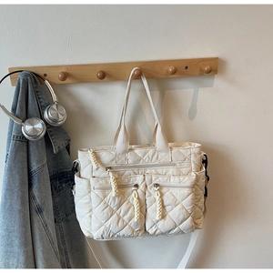 Detail of a quilted cream tote bag featuring large zip pockets and padded fabric texture