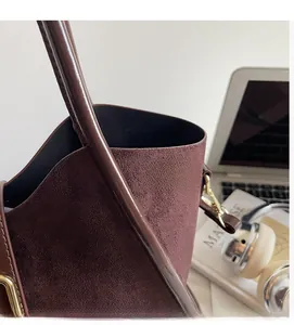 Detail of burgundy suede handbag with soft matte texture and elegant gold metallic clasp
