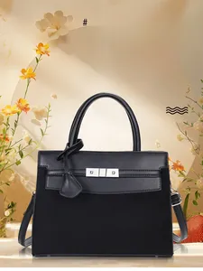 Close-up of black leather and suede handbag featuring a silver turn-lock and handle