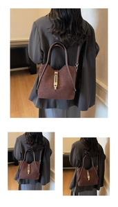 Detailed back view of a dark brown suede handbag with golden buckle and adjustable strap