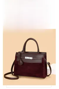 Detail of burgundy wine red handbag showing suede texture and leather handle craftsmanship
