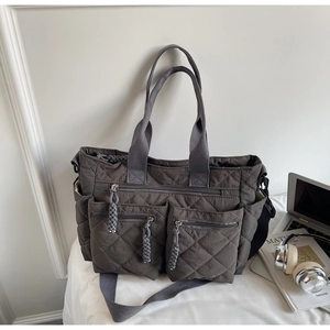 Detail of deep grey quilted nylon tote bag featuring multi-pocket design and crossbody strap