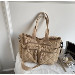 Detail view of khaki quilted tote bag featuring multiple zipper pockets and nylon texture