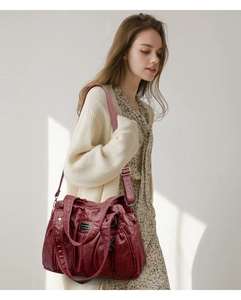 Detail of burgundy shoulder bag with pleated texture and adjustable strap in street style