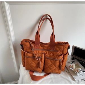 Detail of orange quilted tote bag with multi-pocket design and woven handles for daily use