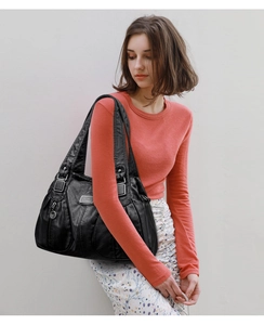 Detail view of large black shoulder bag with pleated texture and side pockets on model