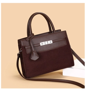 Macro detail of brown leather and suede stitching on tote bag with silver hardware