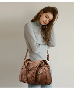 Detail view of dark brown vintage faux leather shoulder bag with pleated texture and silver zippers