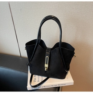 Macro detail of black suede tote bag featuring a golden metallic buckle and leather handles