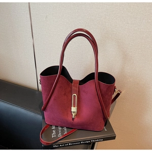 Detail of burgundy velvet bucket bag with glossy patent handle and gold metal buckle