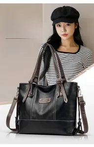 Macro detail of black commuter tote bag with brown straps and white contrast stitching