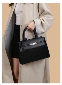 Detail of classic black Kelly-style handbag featuring matte texture and silver hardware