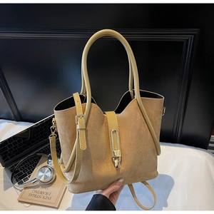 Close-up of khaki suede tote bag with round handle and vertical metal buckle detail