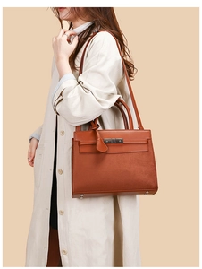 Detail view of the brown leather and suede handbag shown on a model in a trench coat