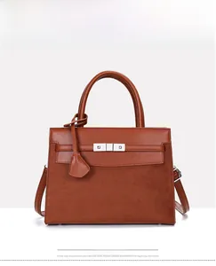 Detail of brown leather and suede stitching on shoulder bag with metal buckle closure