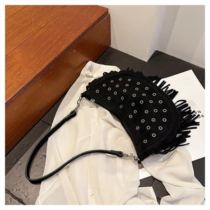 Détail d'un sac besace noir en daim avec œillets métalliques argentés et finitions franges