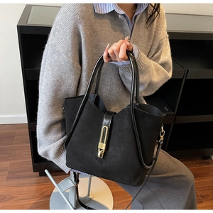Detail of elegant black suede handbag with gold clasp and adjustable shoulder strap
