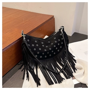 Détail du sac hobo en daim noir avec œillets argentés et franges sur marches en bois