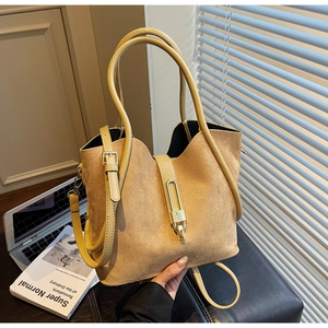 Detailed close-up of yellow suede tote bag with golden metal lock and long shoulder strap
