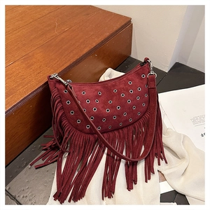 Gros plan détaillé d'un sac besace en daim bordeaux avec œillets et longues franges
