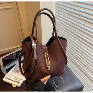 Detailed shot of coffee suede handbag with gold metal clasp and adjustable leather strap