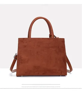 Front view of caramel brown suede handbag with smooth leather handles and metal feet