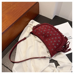 Détail du sac de selle en daim bordeaux avec œillets métalliques et longues franges
