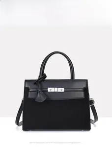 Detail of the black leather and suede bag showing metal clasp and adjustable strap
