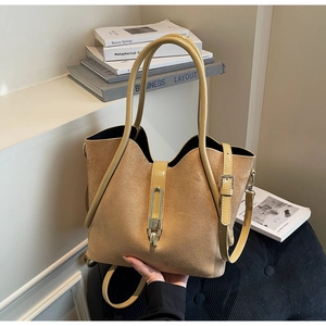 Detail of khaki suede tote bag featuring glossy leather handles and adjustable shoulder strap