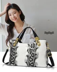 Detail of white cowhide handbag with grey python pattern and gold metal handle