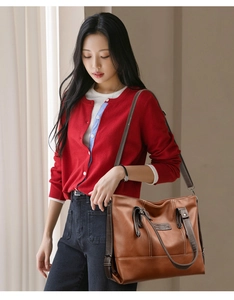 Detailed view of brown leather tote bag with contrast stitching and shoulder strap