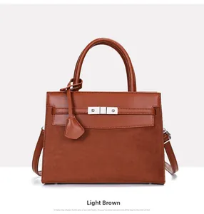 Detail of tan structured handbag with silver metal lock and textured suede panel